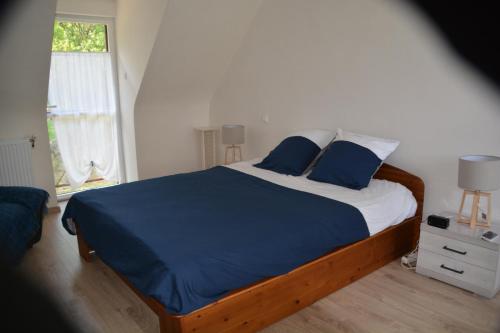 a bedroom with a bed with blue sheets and a window at Kerkleir in Saint-Gilles-Pligeaux