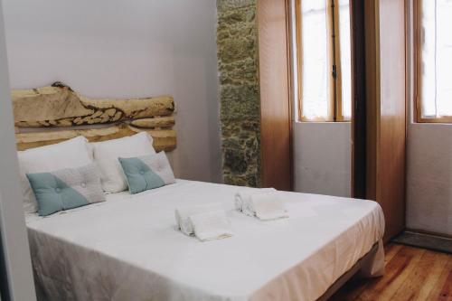 uma cama branca num quarto com duas janelas em Siglas & Runas II na Póvoa do Varzim