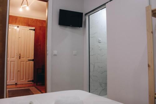 a bedroom with a shower and a television on a wall at Siglas & Runas II in Póvoa de Varzim