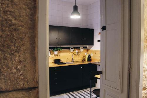 a kitchen with black cabinets and a sink at Siglas & Runas II in Póvoa de Varzim