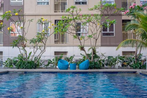a hotel with a swimming pool in front of a building at Titanium Express HomTel in Jakarta