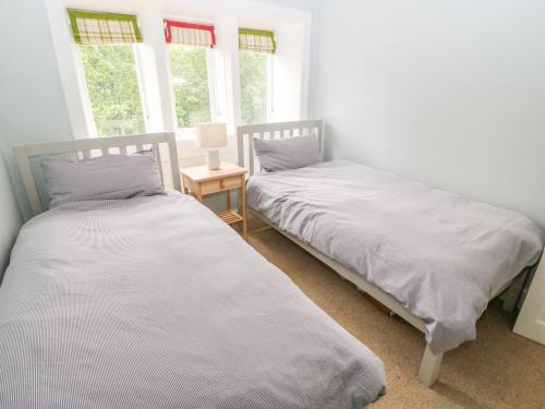 two beds in a room with two windows at Bamforth Cottage in Holmfirth