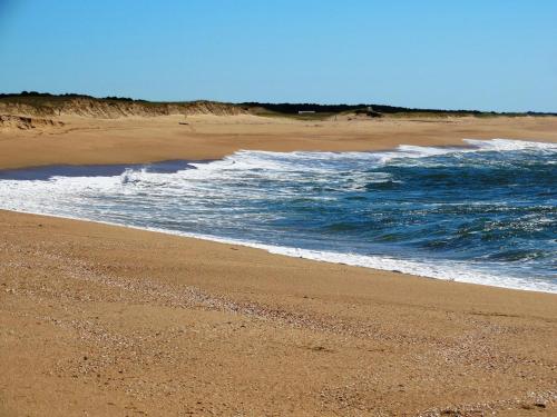 a sandy beach with waves coming in from the ocean at Aloha Village in La Pedrera