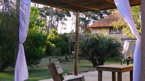 a porch with a wooden table and a bench at Aloha Village in La Pedrera