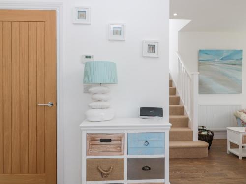 a room with a dresser with a lamp and a staircase at Waterside in Chathill