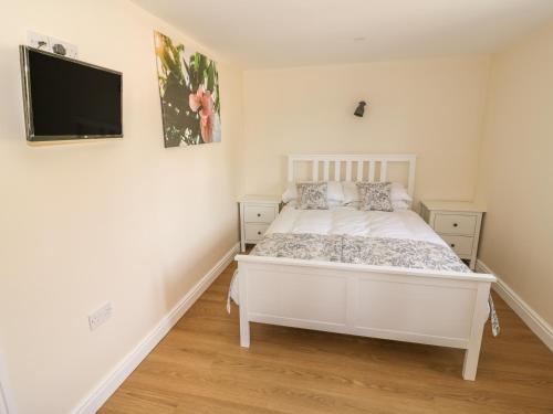 Schlafzimmer mit einem weißen Bett und einem Flachbild-TV in der Unterkunft Cider Cottage in Stratford-upon-Avon