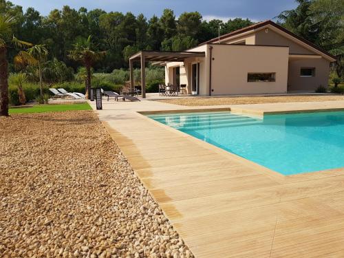 a swimming pool with a wooden deck and a house at Folco Studio Apartment in Piazza Armerina