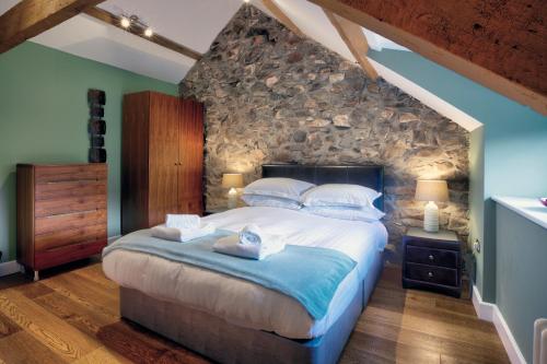 a bedroom with a large bed with a stone wall at The Hay Barn - Llyn Peninsula in Nefyn