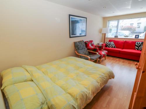 ein Schlafzimmer mit einem Bett und einem roten Sofa in der Unterkunft Lliwedd in Pwllheli