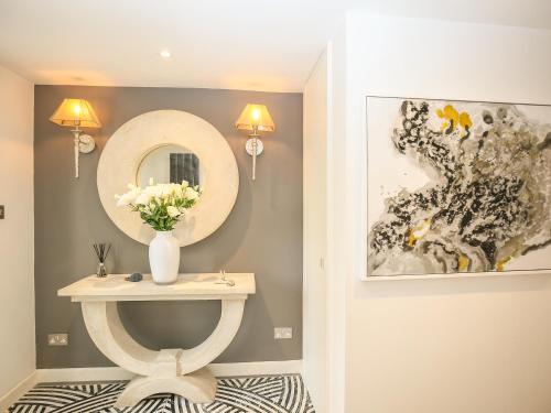 a bathroom with a table with a mirror and a vase of flowers at Shutts House Garden Apartment in Salisbury
