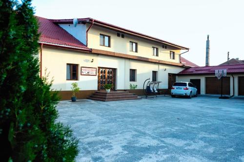 a building with a car parked in a parking lot at Pensiunea Marmis in Rîu Bărbat