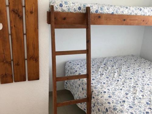 ein Etagenbett aus Holz mit einer Leiter neben einem Bett in der Unterkunft Senya salvi 12 in Sant Feliu de Guixols