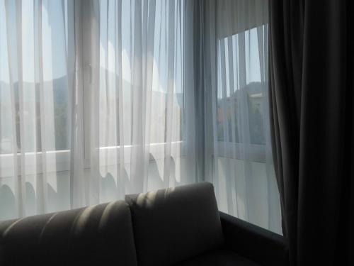 a couch in front of a window with white curtains at Pension Elisabeth - Rooms & Apartments in Salzburg
