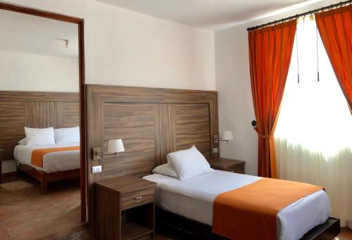 a hotel room with two beds and a mirror at Hotel San Miguel in Contepec