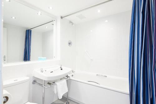 a white bathroom with a sink and a mirror at Alma Lodge Hotel in Stockport