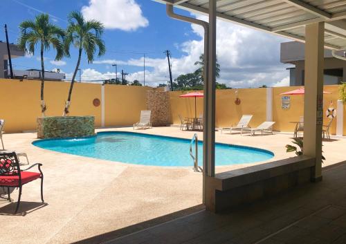 einen Pool mit einem roten Stuhl neben einem Gebäude in der Unterkunft Hotel Villa del Sol in San Juan