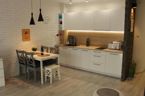 a kitchen with white cabinets and a table and chairs at Sunny Adventure Baltic Apartament in Pobierowo