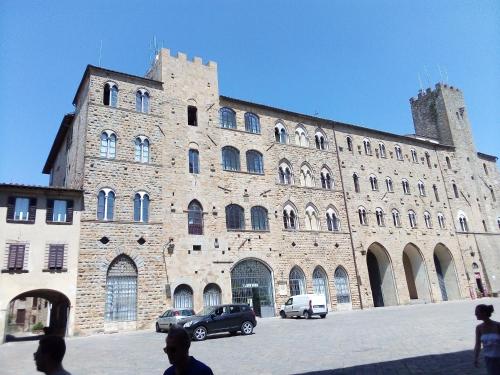 a large brick building with cars parked in front of it at volterracentro in Volterra