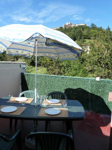 a blue table with an umbrella on a balcony at Maison Baxter in Prats-de-Mollo-la-Preste