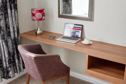 a laptop computer sitting on a wooden desk with a chair at Alma Lodge Hotel in Stockport