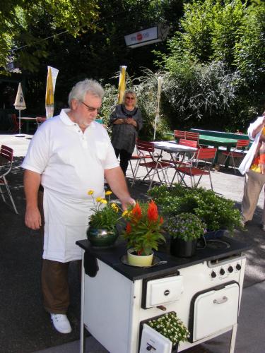 a man in an apron standing next to a table with plants at Landhaus Gritschacher in Sankt Peter in Holz