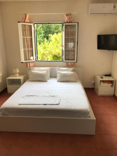 sypialnia z dużym łóżkiem i oknem w obiekcie Inglessata Rose w mieście Svoronata