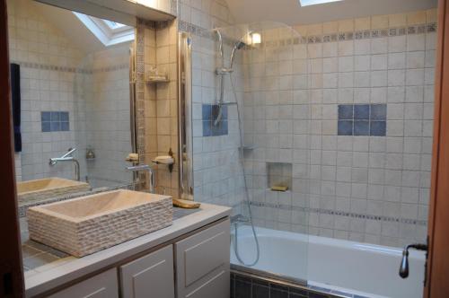 La salle de bains est pourvue d'une baignoire, d'un lavabo et d'une douche. dans l'établissement Gîte Mi Do, à Tourly