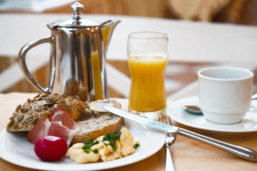 a plate of food with a tea kettle and a cup of orange juice at Thermenhotel Quellenhof in Bad Füssing