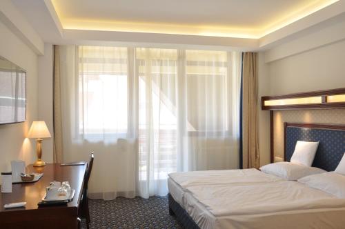 a hotel room with a bed and a desk and a window at Centrum Hotel in Debrecen