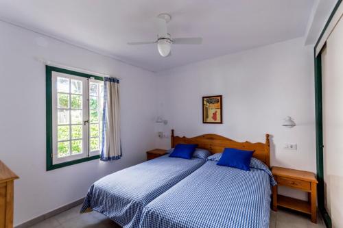 a bedroom with a bed with blue sheets and a window at Apartamentos Las Brisas I & II in Cala'n Bosch