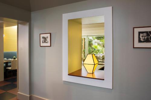 a mirror on a wall with a yellow lamp on a table at Hôtel A La Villa des Artistes in Paris