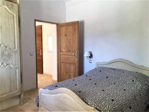 a bedroom with a bed and a wooden door at Coquet 2 pièces au calme avec piscine (2/4 pers) in Fontvieille