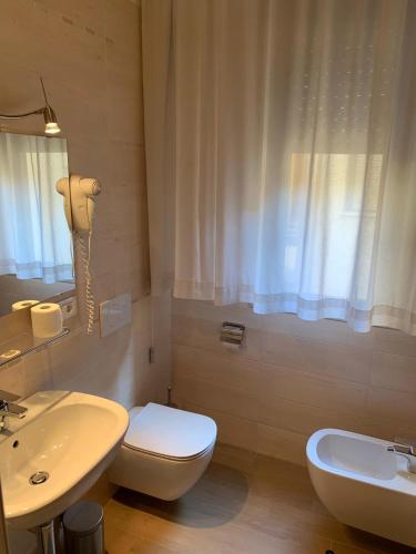 a bathroom with a white toilet and a sink at Hotel Centrale in Este