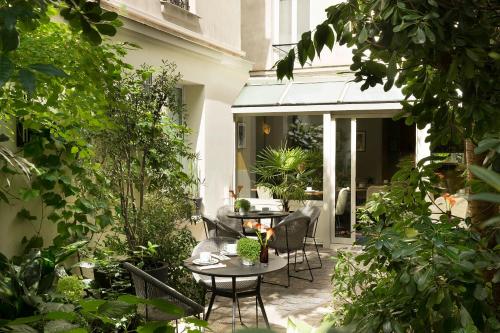 a patio with tables and chairs and plants at Hôtel A La Villa des Artistes in Paris