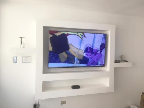 een flatscreen-tv zittend op de top van een witte muur bij Water Front Peaceful Apartment in San Juan