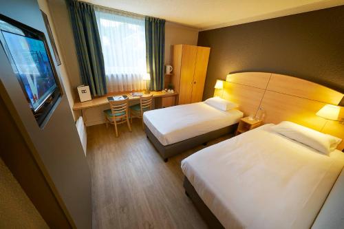 a hotel room with two beds and a desk at DC Hotel & Restaurant Brussels South in Brussels