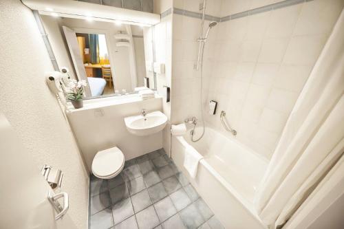 a bathroom with a toilet and a tub and a sink at DC Hotel & Restaurant Brussels South in Brussels