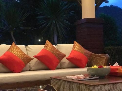 a white couch with colorful pillows on a table at Papai Country Lodge SHA in Ban Mae Pong