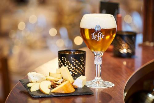a glass of beer and a plate of cheese at DC Hotel & Restaurant Brussels South in Brussels