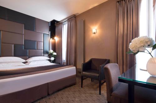 a hotel room with a bed and a chair and a desk at Hôtel A La Villa des Artistes in Paris