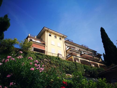 a building on top of a hill with flowers at Bellavista Eremitaggio in Torri del Benaco