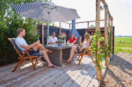 a group of people sitting at a table under an umbrella at Wellnessappartement 't Wechtertje in Wijhe