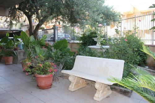 a white bench sitting in a garden with plants at B&B Ulivo in Trabia