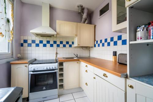 a kitchen with white cabinets and blue and white tiles at Votre appartement à Poissy in Poissy