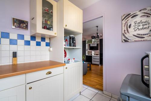 a kitchen with white cabinets and blue and white tiles at Votre appartement à Poissy in Poissy