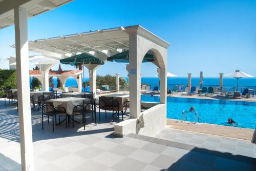 een patio met een tafel en stoelen en een zwembad bij Mouikis Sun Village in Lakíthra