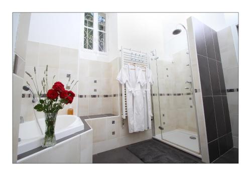 a bathroom with a vase with red roses in it at Villa Aimée Luxury Apartments with Heated Pool in Vals-les-Bains