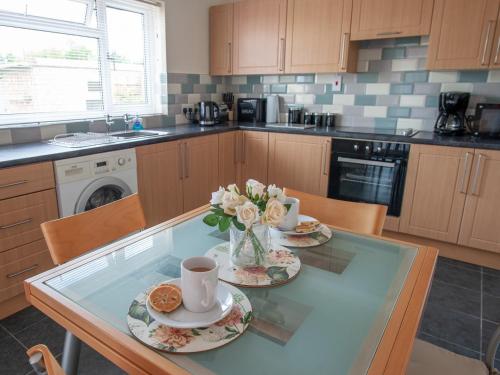 a kitchen with a glass table with two plates and flowers at Cwtch Y Coetir in Swansea