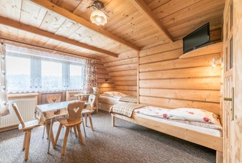 uma cabina de madeira com 2 camas e uma secretária em Pokoje Gościnne Sarenka - noclegi w pobliżu Tatr em Czarna Góra