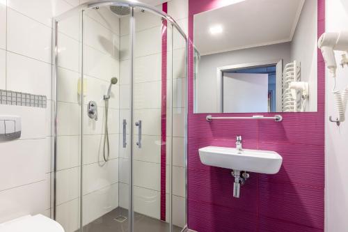 a bathroom with a sink and a glass shower at Hotel Perłowy in Okuninka